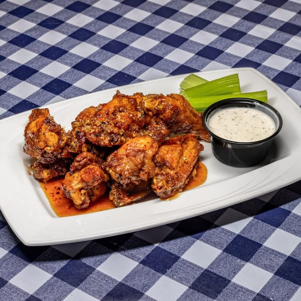 Bono Pizza & Pasta's chicken wings with celery sticks and ranch dressing on a checkered tablecloth.