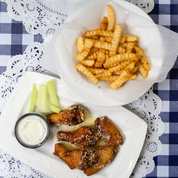 Garlic parmesan chicken wings with celery sticks, ranch, and a side of crinkle-cut fries.