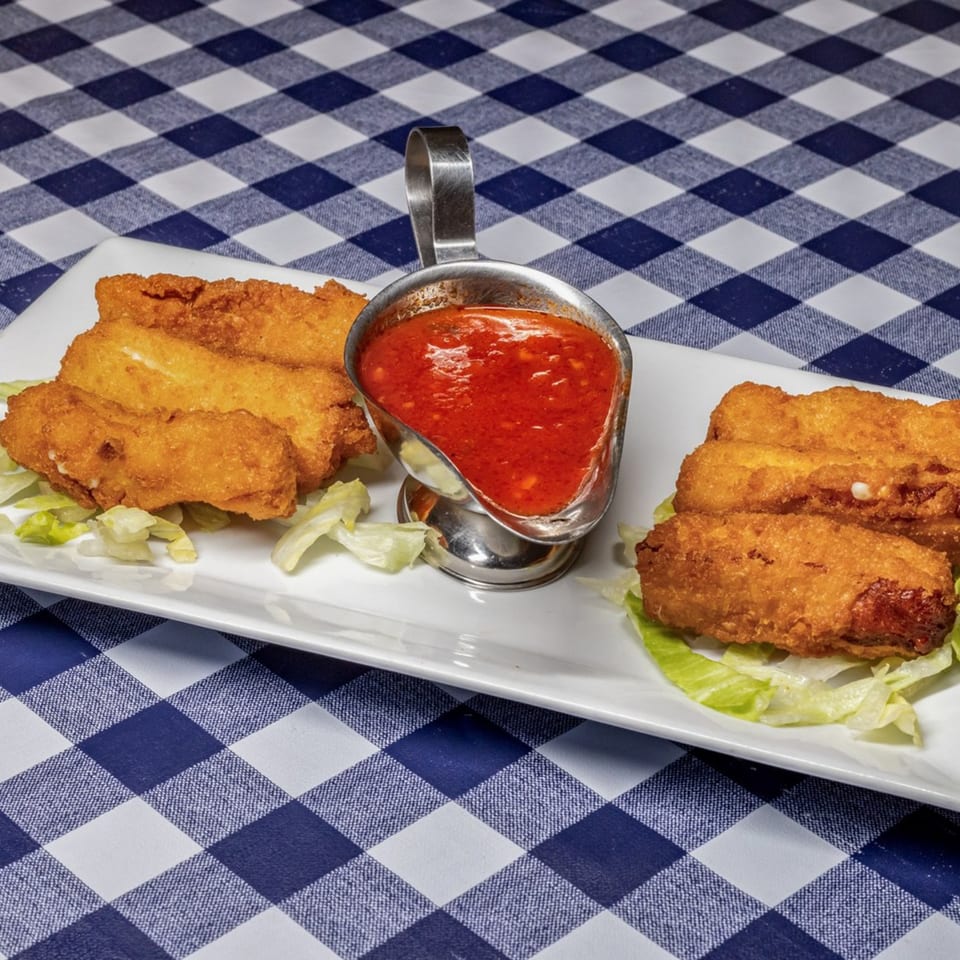 Golden-brown fried mozzarella sticks with a side of red marinara sauce on a white plate.