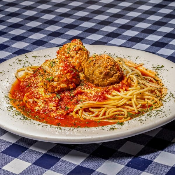 Spaghetti with three large meatballs, marinara sauce, and parsley on a white plate.
