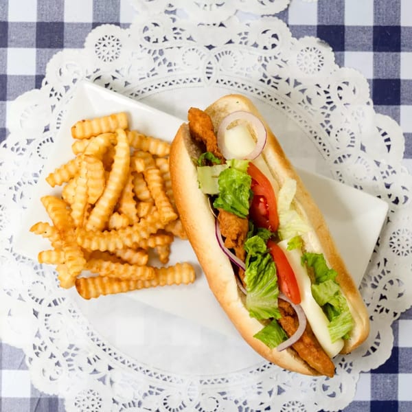 Crispy chicken sandwich with lettuce, tomato, onion, and mayonnaise, served with crinkle-cut fries.
